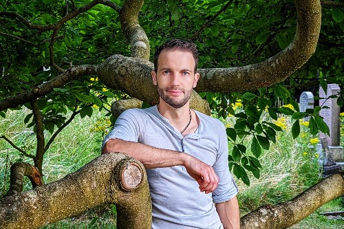 Dr Chris Clements poses in front of a tree.